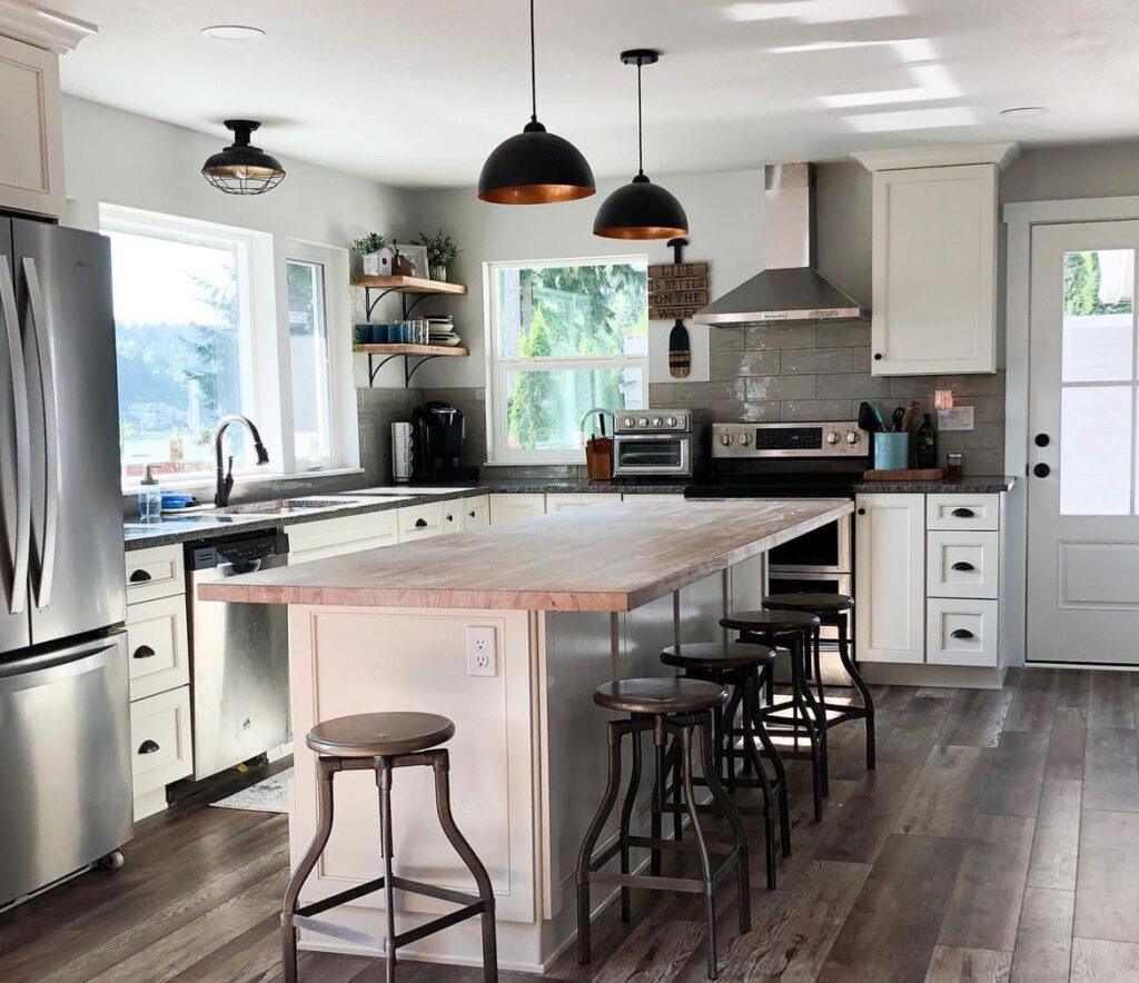 Remodeled kitchen with white cabinets, butcher-block island seating, black pendant lights and range hood in Kitsap County, WA